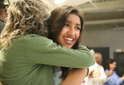 A student hugs her teacher at a moving up ceremony.