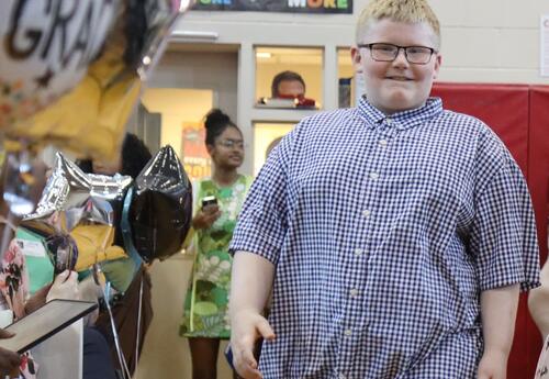 A students walks down an aisle to graduate.