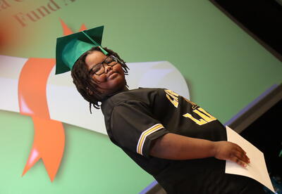 A student walks across the stage with a certificate.