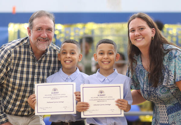 Twin brothers posing for a photo with their fifth-grade teachers