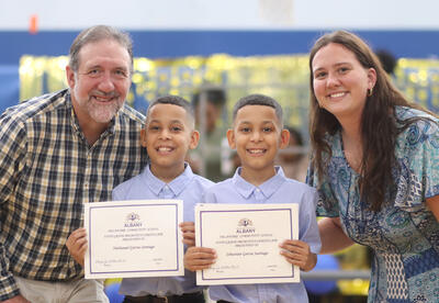 Twin brothers posing for a photo with their fifth-grade teachers