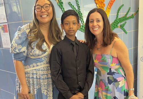 A student poses after graduation with his teachers.