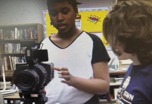 A students works with another student to make a video.
