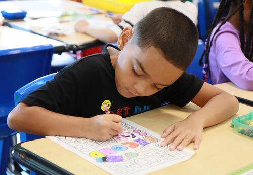 Overhead view of a student drawing with crayons