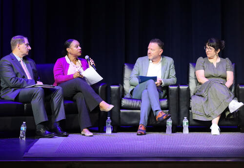 Four panelists dialoguing on stage