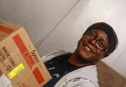 A cafeteria worker takes inventory of a food delivery.