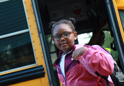 A students exits the bus on the first day of school.