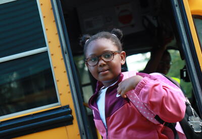 A students exits the bus on the first day of school.