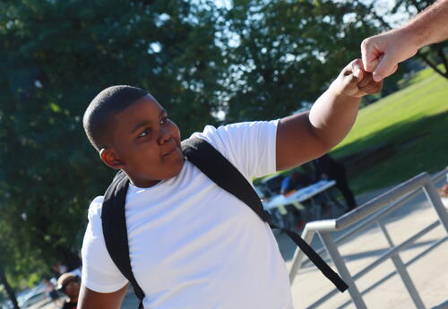 A student high fives a teacher on the first day of school.
