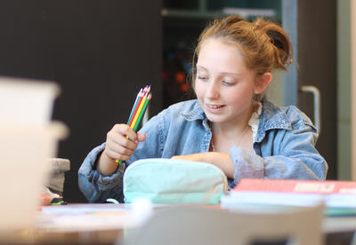 Student smiling while sorting school supplies