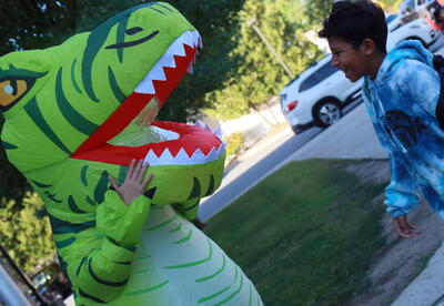 A teacher in an inflatable costume greets a student.