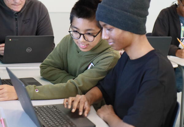 Two students work together on a Chromebook.