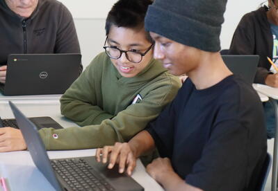 Two students work together on a Chromebook.