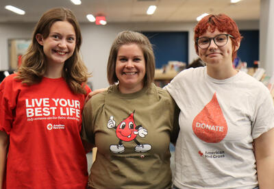 Two students posing with blood drive club adviser Alicia Abdul