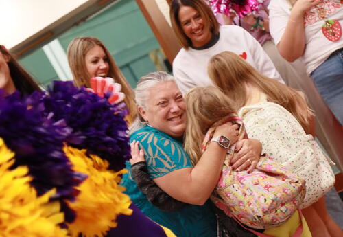 A teacher hugs a student at a clap in event.
