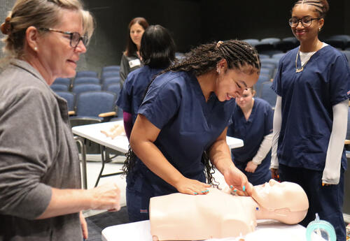 Health science student practicing checking for a pulse on a medical manikin