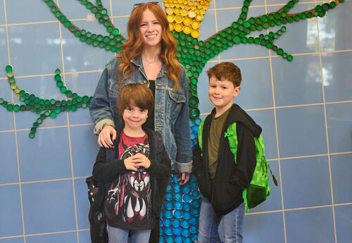 A parent and two students pose before a school breakfast event.
