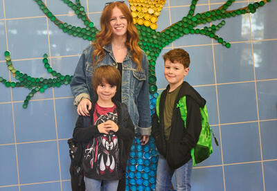 A parent and two students pose before a school breakfast event.