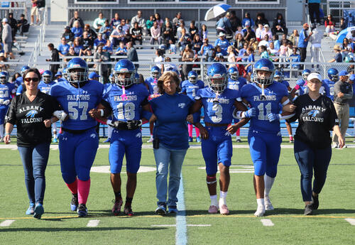 Football players walking on the field with 91��ɫ High administrators and athletic director