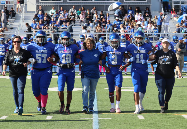 Football players walking on the field with 91��ɫ High administrators and athletic director