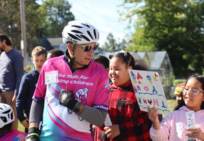 Students cheer on cyclists spreading awareness about missing and exploited children.