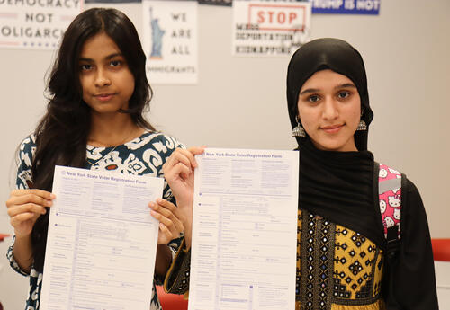 Students holding up blank voter registration ballots