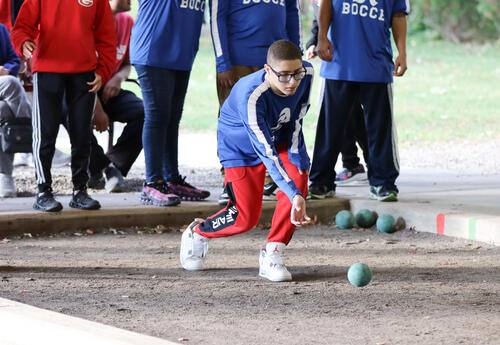 Albany High student-athlete throwing a bocce ball as teammates look on