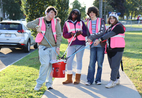 Four students posing with trash buckets and trash grabbers