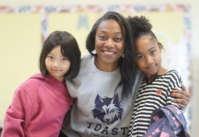 Ty Richards posing for a photo with two students