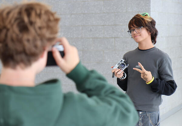 Photography I students; one student taking a photo of another