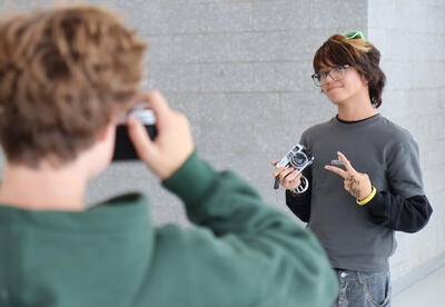 Photography I students; one student taking a photo of another