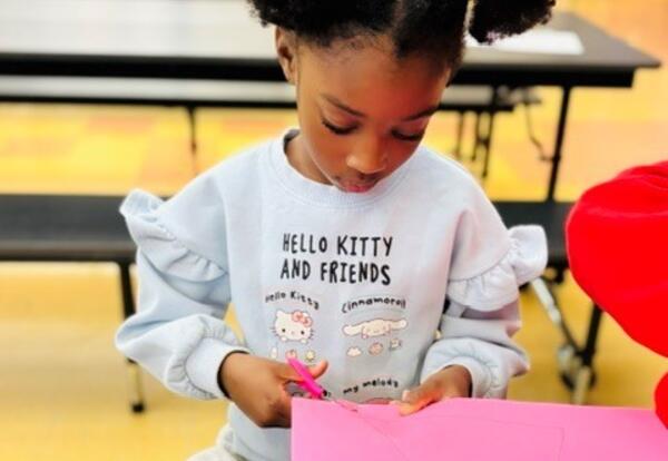 A student completes a fall-themed craft at a literacy event.