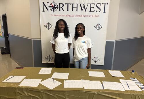 Two ladies standing at sign in table