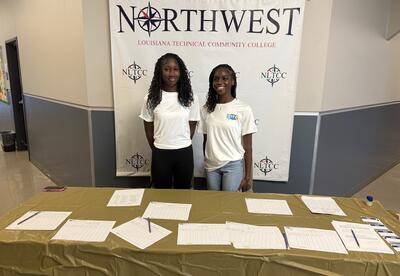 Two ladies standing at sign in table