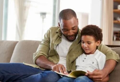 Father sitting on the coach reading with his son