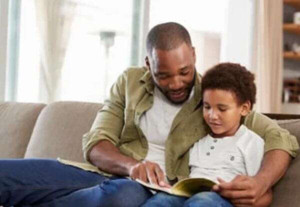 Father sitting on the coach reading with his son