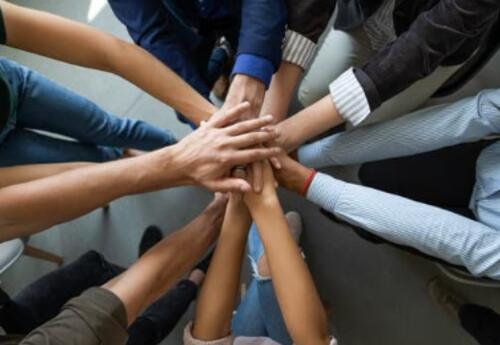 A group of people in a huddle with their hands on top of each other