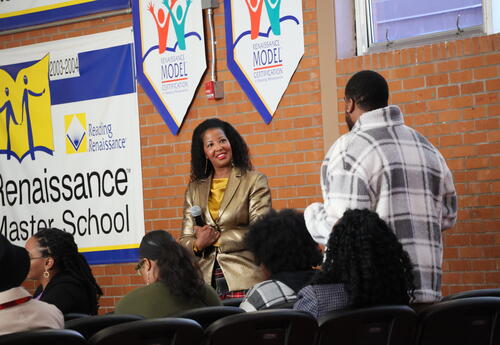 A woman speaker looking at a guest standing up answering a question in an event setting