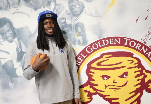Zechariah Jenkins head shot, blue hat, gray shirt, holding a football