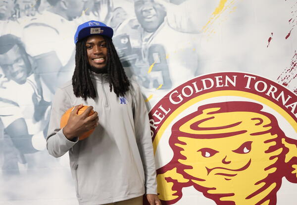 Zechariah Jenkins head shot, blue hat, gray shirt, holding a football