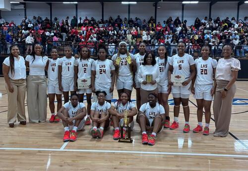 Lady Tornadoes basketball team posing for picture while holding awards