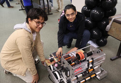 Two LHS students kneeled down working on a robot.
