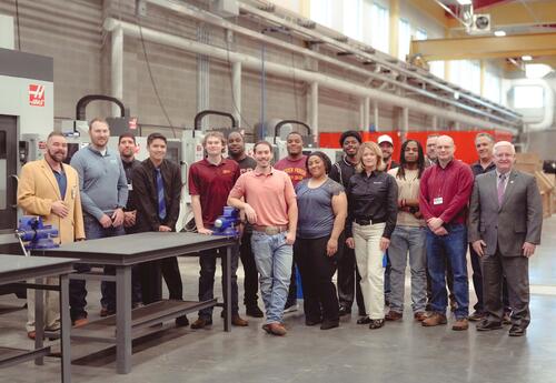 Group of people smiling; standing in an industrial looking room