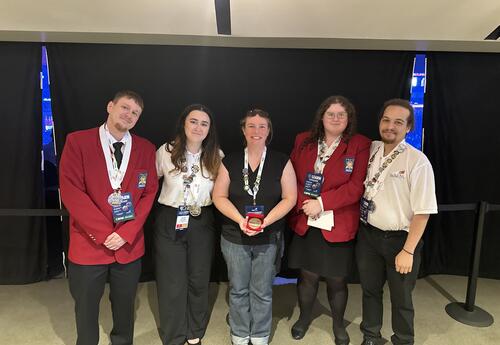 Group of people posing for a photo, some wearing silver medals