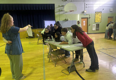 Rock Island Elementary students lean in and squint to read a page through unfamiliar glasses-part of the IDEA Project’s vision simulation on understanding different abilities.