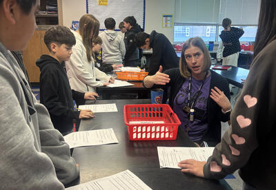 Sterling Junior High science teacher Susan Honaas works with students during a hands-on physics lesson exploring Newton’s First Law of Motion.