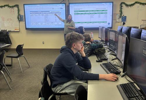 Eastmont High School students analyze pay stubs and tax forms as part of a Financial Literacy lesson focused on real-world money management skills.