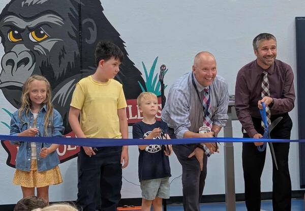 The Lincoln superintendent and principal stand with three students getting ready to cut a blue ribbon. All are holding scissors.