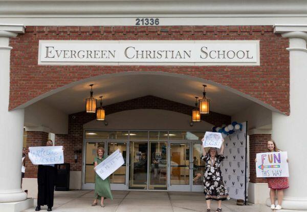 Teachers holding welcome back signs
