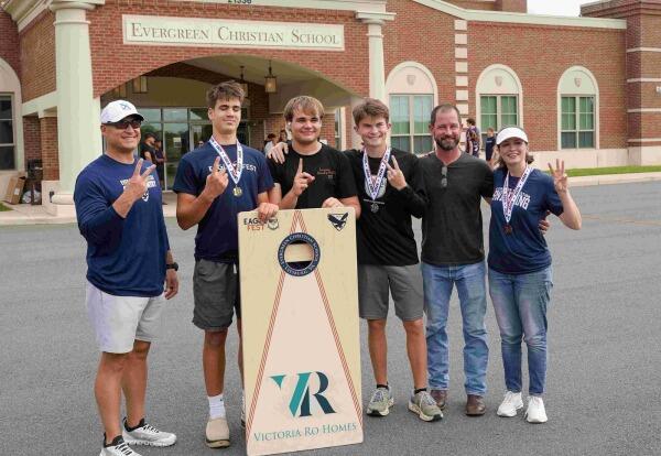 Six cornhole winners with their board